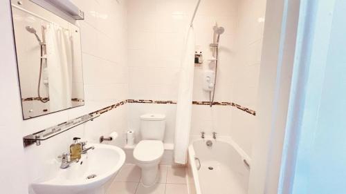 a white bathroom with a toilet and a sink at Preston Hotel in Yeovil