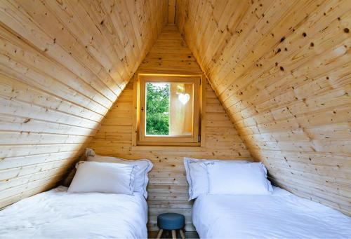 two beds in a wooden room with a window at Lipa Plac in Postojna