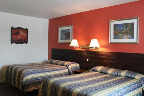two beds in a hotel room with red walls at Auberge - Motel Le Pigeonnier in Farnham