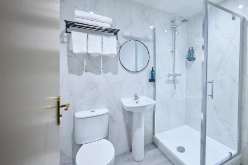 a white bathroom with a shower and a toilet and a sink at Temple Bar Townhouse in Dublin