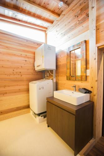 a bathroom with a sink and a washer and dryer at ファーストアベニューハウス 駅近 1組限定貸切 in Anan