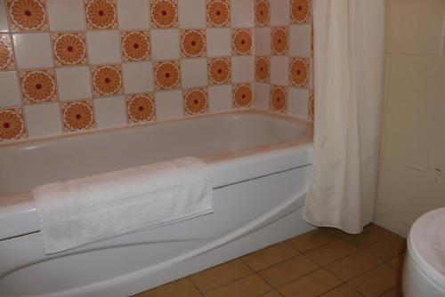 a bathroom with a bath tub with a towel on it at Auberge - Motel Le Pigeonnier in Farnham