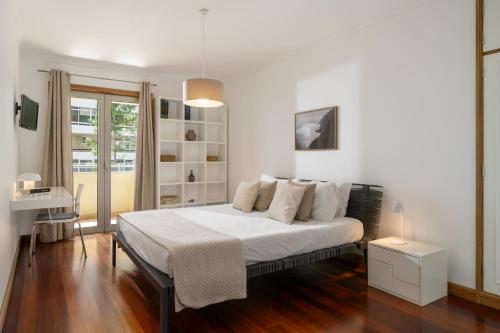 1 dormitorio con cama con sábanas blancas y escritorio en Arcadas III by An Island Apart, en Funchal