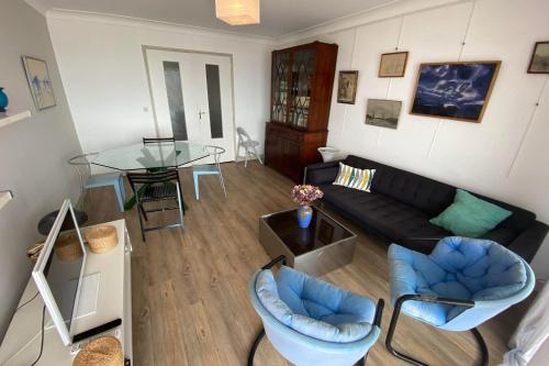 - un salon avec un canapé noir et une table en verre dans l'établissement Spacious bright nest with balcony facing the sea, à Pornichet