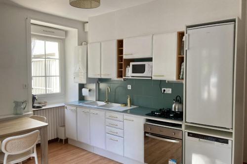 une cuisine avec des armoires blanches et un réfrigérateur blanc dans l'établissement Apartment with parking in city center, à Pornichet