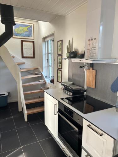 a kitchen with a stove and a staircase at Charmerende Byhus in Brønderslev