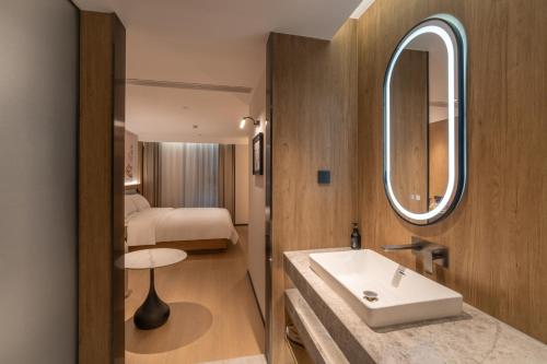 d'une salle de bains avec lavabo et d'une chambre. dans l'établissement Shanghai Qiyu Hotel, The Bund Yuyuan Branch, à Shanghai