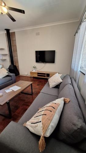 a living room with a gray couch and a flat screen tv at 21 on Main in Benoni