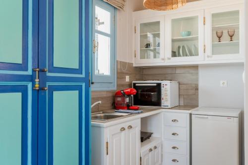 a kitchen with white cabinets and a red appliance at La Casa Tinos 22 in Agios Ioannis Tinos