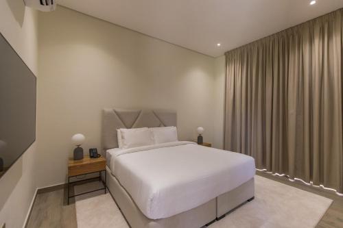 a bedroom with a white bed and a window at Ivory House Resort - Ophiolite in Hatta