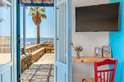 a door to a room with a view of a palm tree at La Casa Tinos 22 in Agios Ioannis Tinos