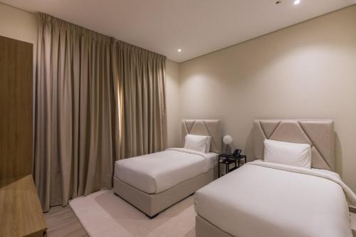 two beds in a hotel room with curtains at Ivory House Resort - Ophiolite in Hatta