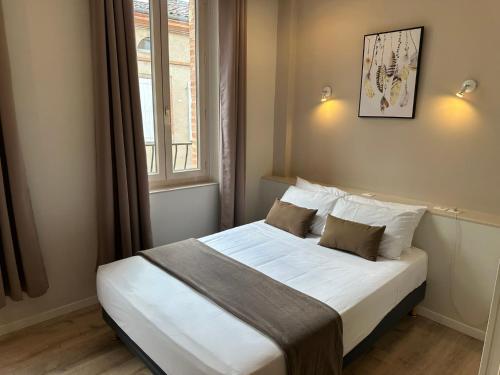 a bedroom with a bed with white sheets and a window at Hotel Chiffre in Albi
