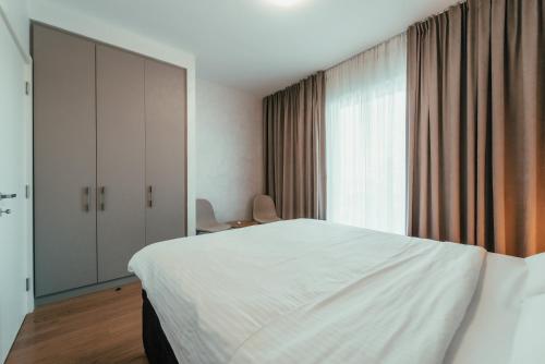 a bedroom with a white bed and a large window at BW Cityline Residences in Belgrade