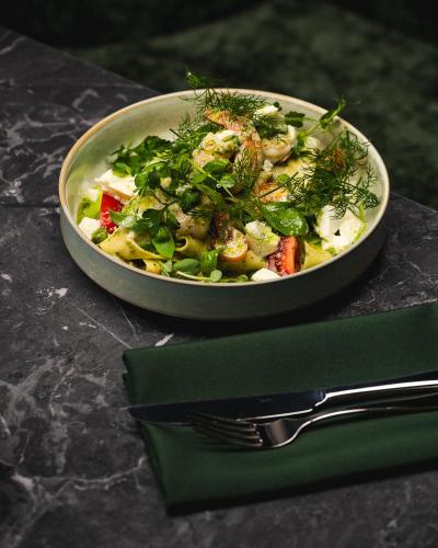 a bowl of salad on a table with a fork at Focus Hotel Premium Wrocław in Wrocław