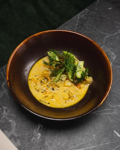 a brown bowl of soup with a garnishment at Focus Hotel Premium Wrocław in Wrocław