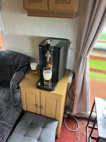 a tv on a table with two glasses of beer at Caravan in Banff