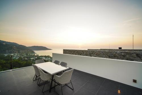 a table and chairs on a balcony with a view of the ocean at Sea Theatre Kata by ROI in Ban Nong Chaeng