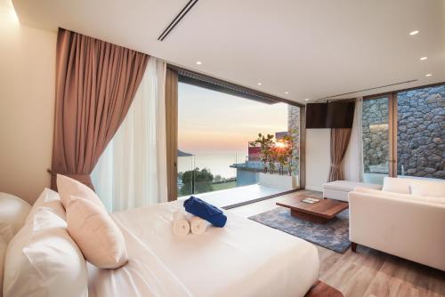 a bedroom with a white bed and a large window at Sea Theatre Kata by ROI in Ban Nong Chaeng