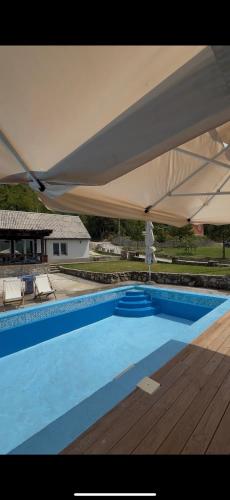 a large blue swimming pool with a large white umbrella at Peaks of Prokletije - Outdoor pool in Gusinje