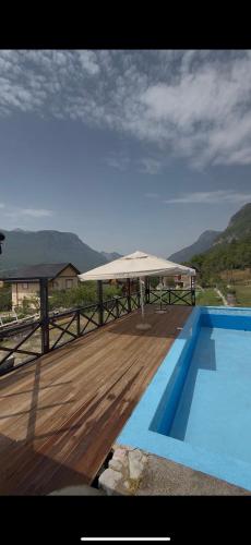 a patio with a white umbrella next to a swimming pool at Peaks of Prokletije - Outdoor pool in Gusinje