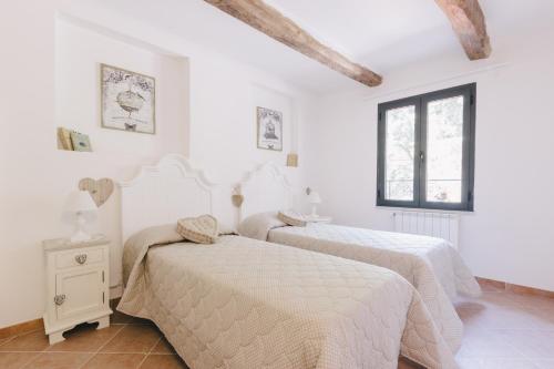 two beds in a bedroom with white walls and a window at Il Cuore delle Apuane in Antona