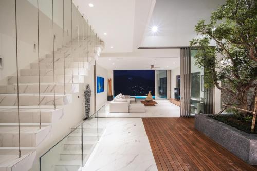an open living room with white furniture and a staircase at Sea Theatre Kata by ROI in Ban Nong Chaeng