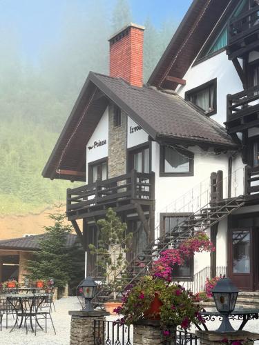a large white building with flowers in front of it at Pensiunea Poiana Izvoarelor in Vatra Dornei