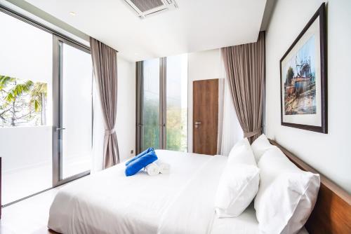 a bedroom with a white bed and large windows at Sea Theatre Kata by ROI in Ban Nong Chaeng