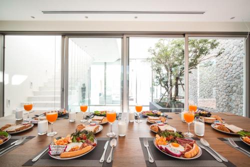 a long table with plates of food and orange juice at Sea Theatre Kata by ROI in Ban Nong Chaeng