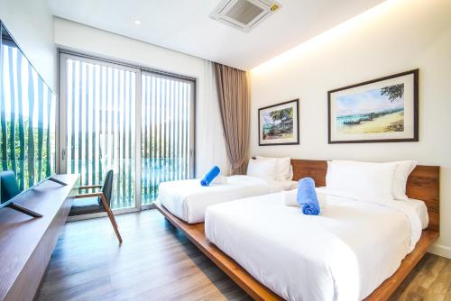 two beds in a room with a large window at Sea Theatre Kata by ROI in Ban Nong Chaeng
