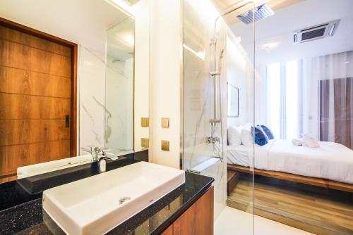 a bathroom with a sink and a shower and a bed at Sea Theatre Kata by ROI in Ban Nong Chaeng