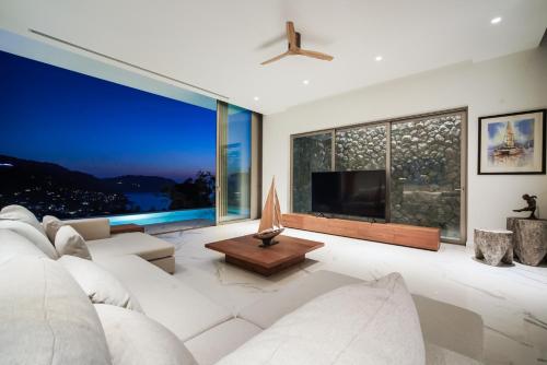 a living room with a white couch and a large window at Sea Theatre Kata by ROI in Ban Nong Chaeng