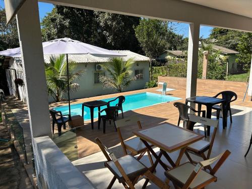 Un patio con mesas y sillas y una piscina. en Recanto Dubom, a 10 minutos do autódromo Goiânia, en Bela Vista de Goiás