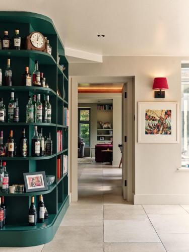 a room with a green book shelf filled with bottles of wine at Kingsley House in Haslemere