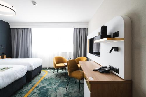 a hotel room with two beds and a desk at Focus Hotel Premium Wrocław in Wrocław