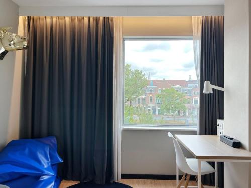 a bedroom with a window with a desk and a table at Holiday Inn - the niu, Dairy Haarlem in Haarlem