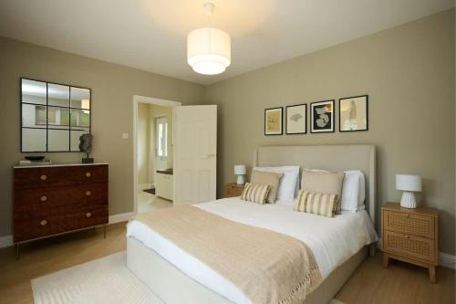 a bedroom with a large white bed and a dresser at The Lindens Garden Retreat - Spacious single-level 4-bed with garden near Maidenhead & River Thames in Maidenhead