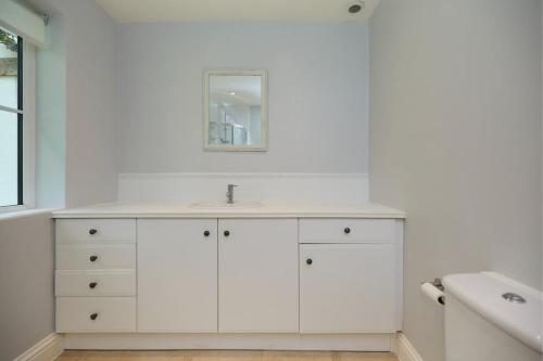 a white bathroom with a sink and a mirror at The Lindens Garden Retreat - Spacious single-level 4-bed with garden near Maidenhead & River Thames in Maidenhead