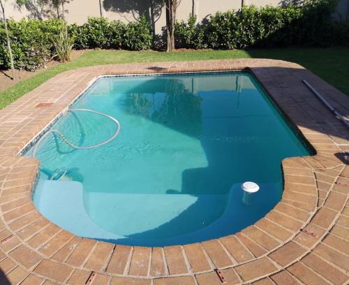 a swimming pool with blue water in a backyard at Jo's Eden in Edenvale