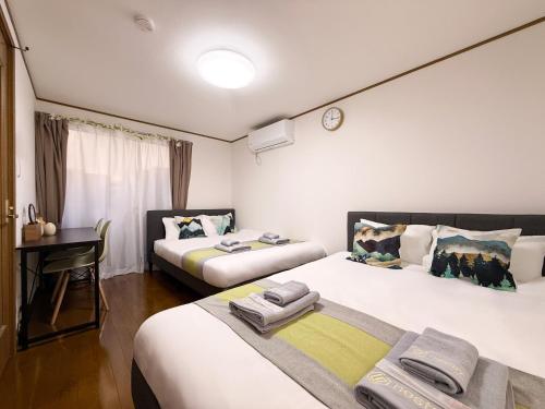 a room with two beds and a desk in it at nestay villa tokyo akasaka in Tokyo