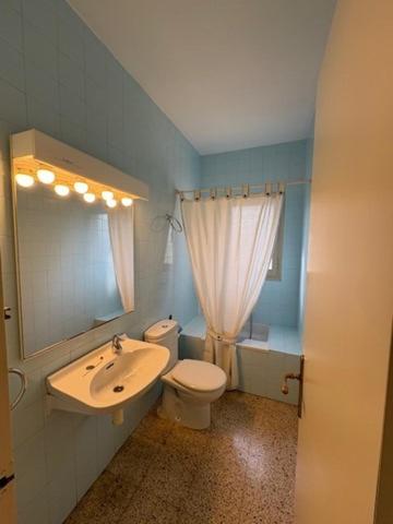 Un baño con lavabo, inodoro y espejo. en Villa Penedes, en Roda de Bará