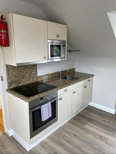a kitchen with white cabinets and a sink and a microwave at Crawford House- ScholarLee Living Apartments in Cork