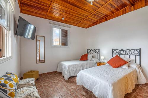 Habitación con 2 camas, TV y sofá. en Casita Pedro El Remo, en Los Llanos de Aridane