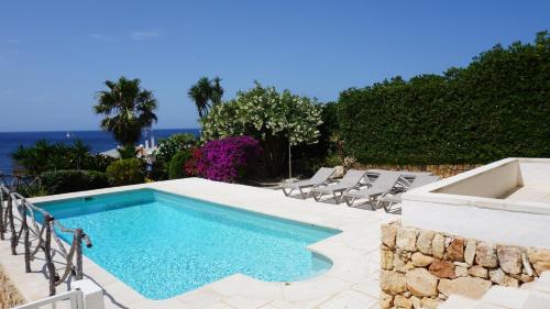 ein Swimmingpool mit Stühlen und das Meer im Hintergrund in der Unterkunft Villa en primera linea de mar cerca de Binibeca in Sant Lluís
