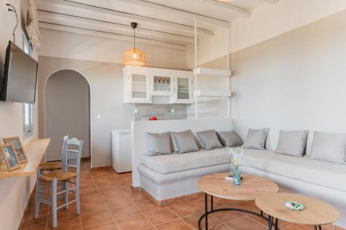 a living room with a white couch and tables at La Casa Tinos 22 in Agios Ioannis Tinos