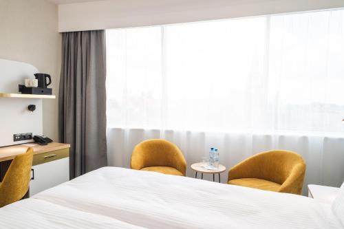 a hotel room with a bed and two chairs at Focus Hotel Premium Wrocław in Wrocław