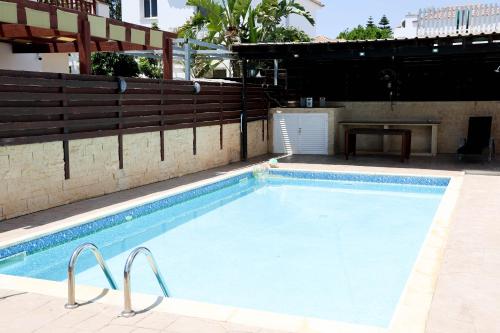 a large swimming pool with a wooden fence and a table at Agesilaos Seaview 33 in Ayia Napa