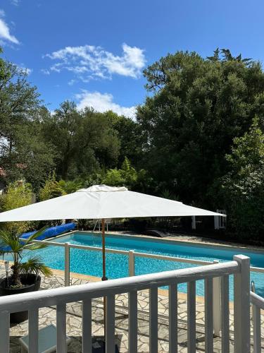 - un parasol blanc à côté de la piscine dans l'établissement Paloma, à Hossegor