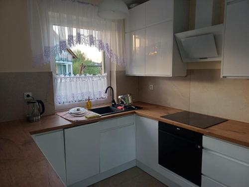 a kitchen with white cabinets and a sink and a window at Willa Przygoda in Żukowo
